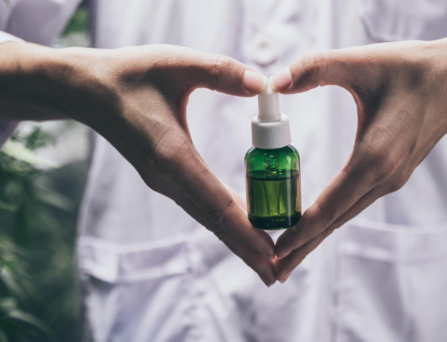 Hands framing a small green oil bottle